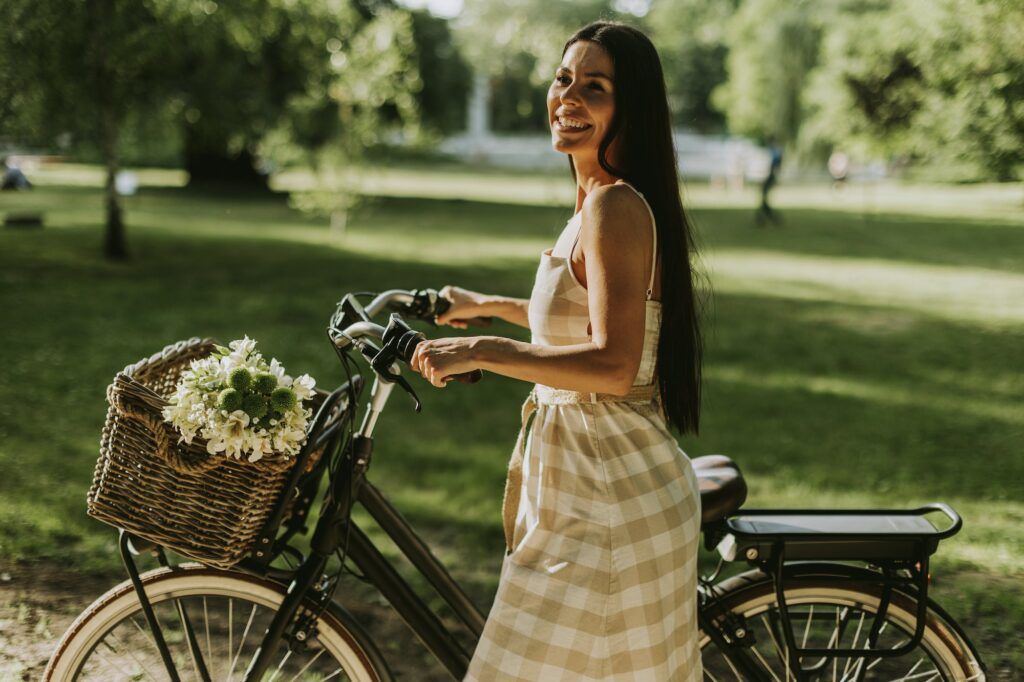 Young woman with electric bike and flowers in the basket