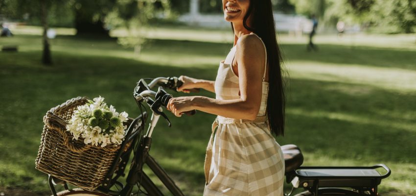 Young woman with electric bike and flowers in the basket